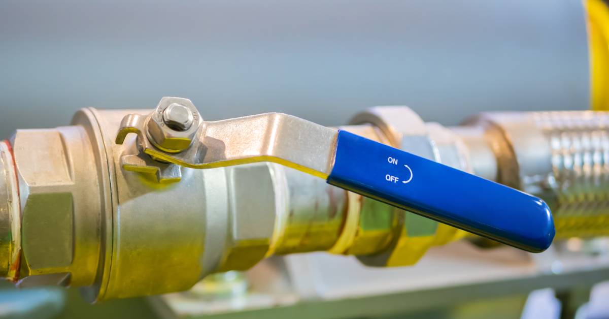 A close-up on a brass lever valve connected to a pipe. The valve lever has a blue handle labelled 'ON/OFF'